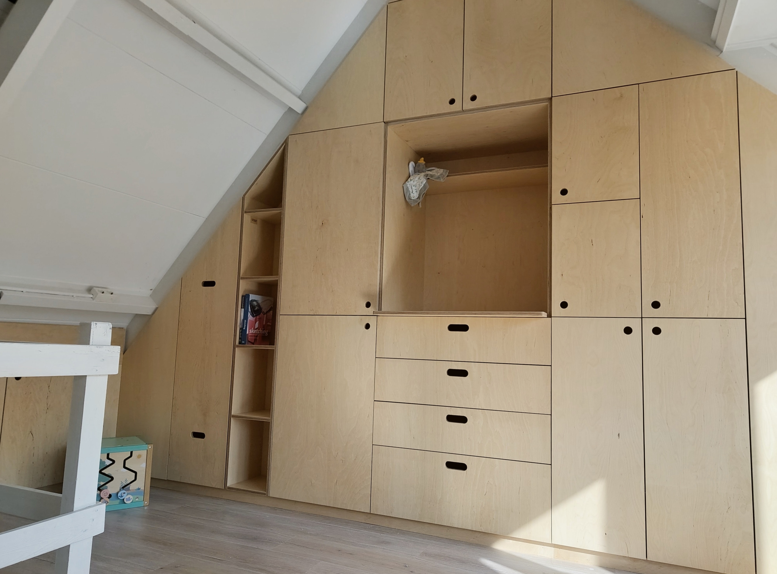 Zolderkast op maat in Amersfoort met schuine wanden en dakkapel. Wandvullende kast met knieschotten en weggewerkte installaties.